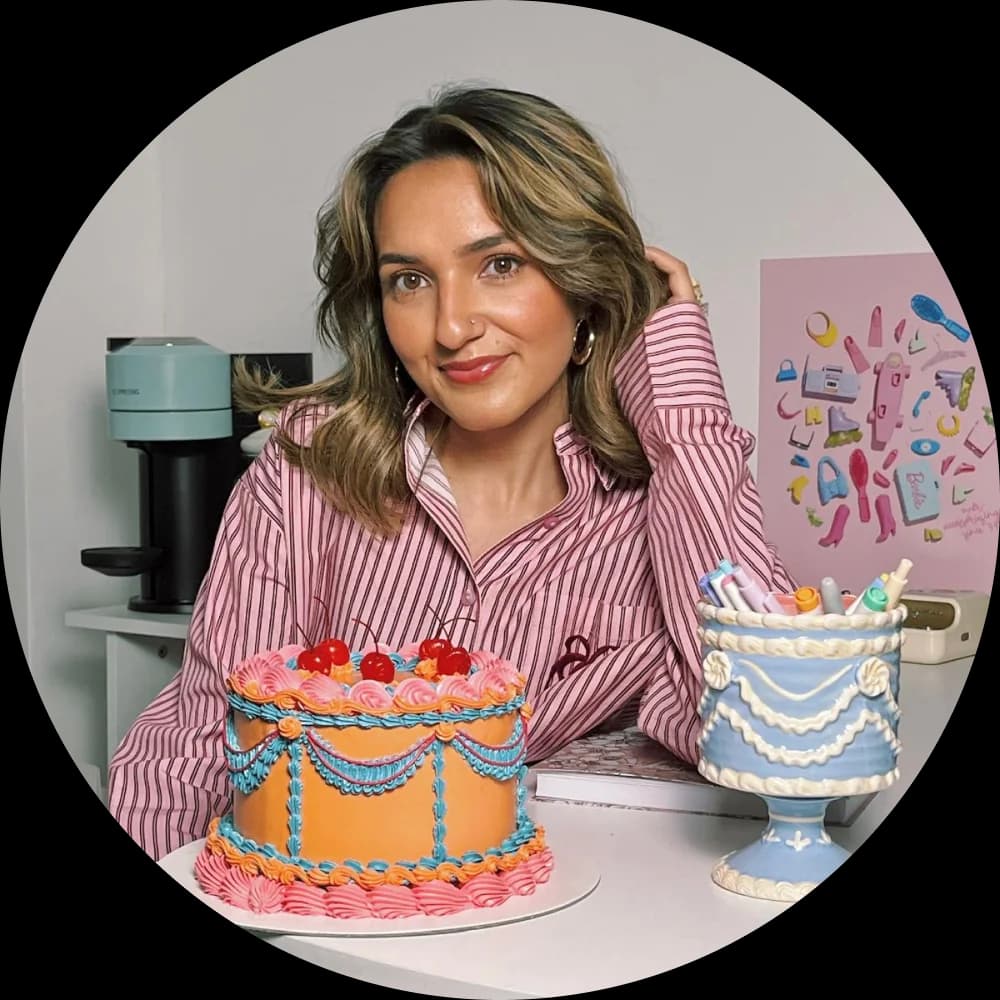 Corinne Mankoo sitting behind two vintage-style cakes in the studio