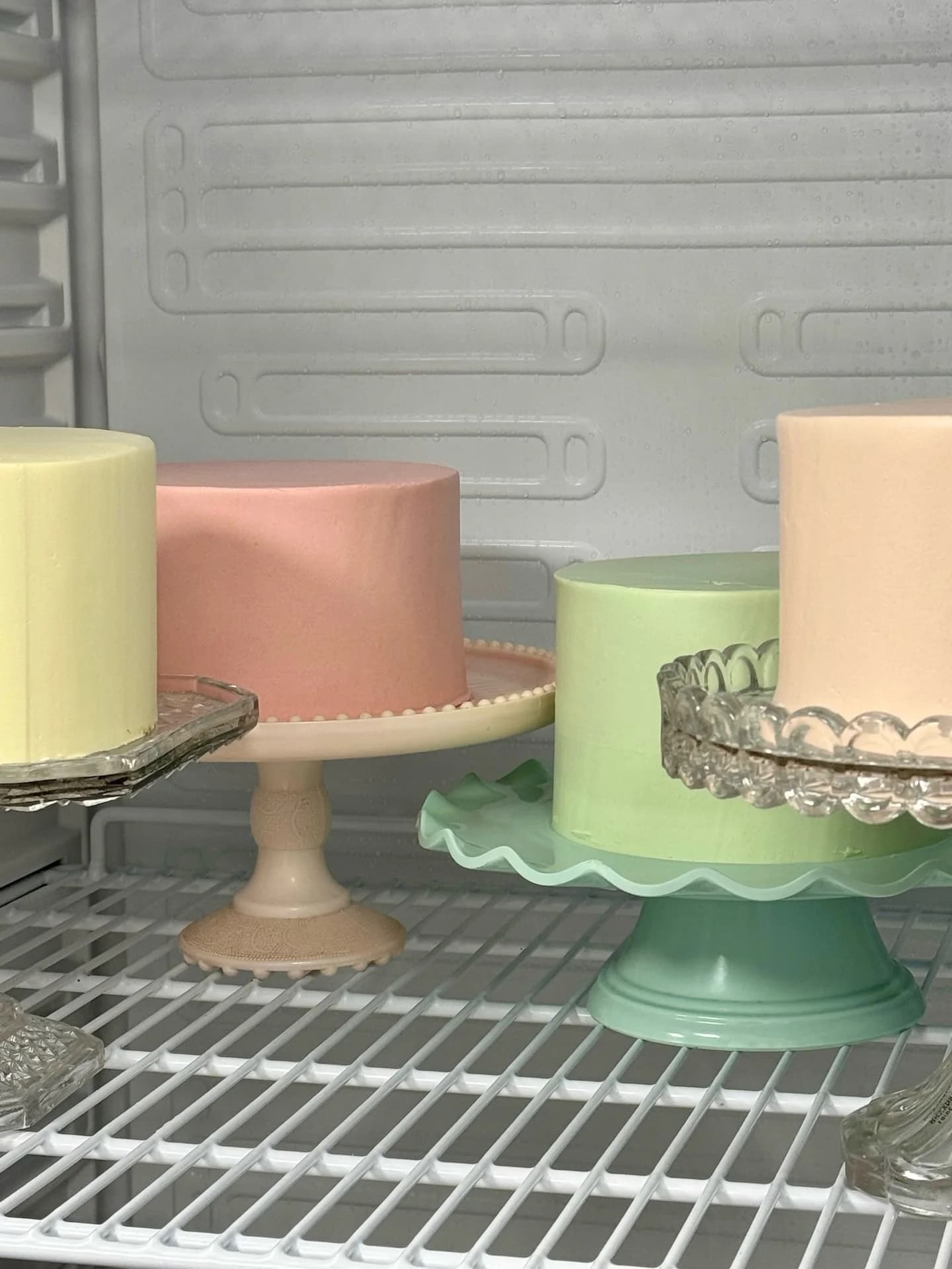 Crumb-coated pastel cakes resting on vintage cake stands