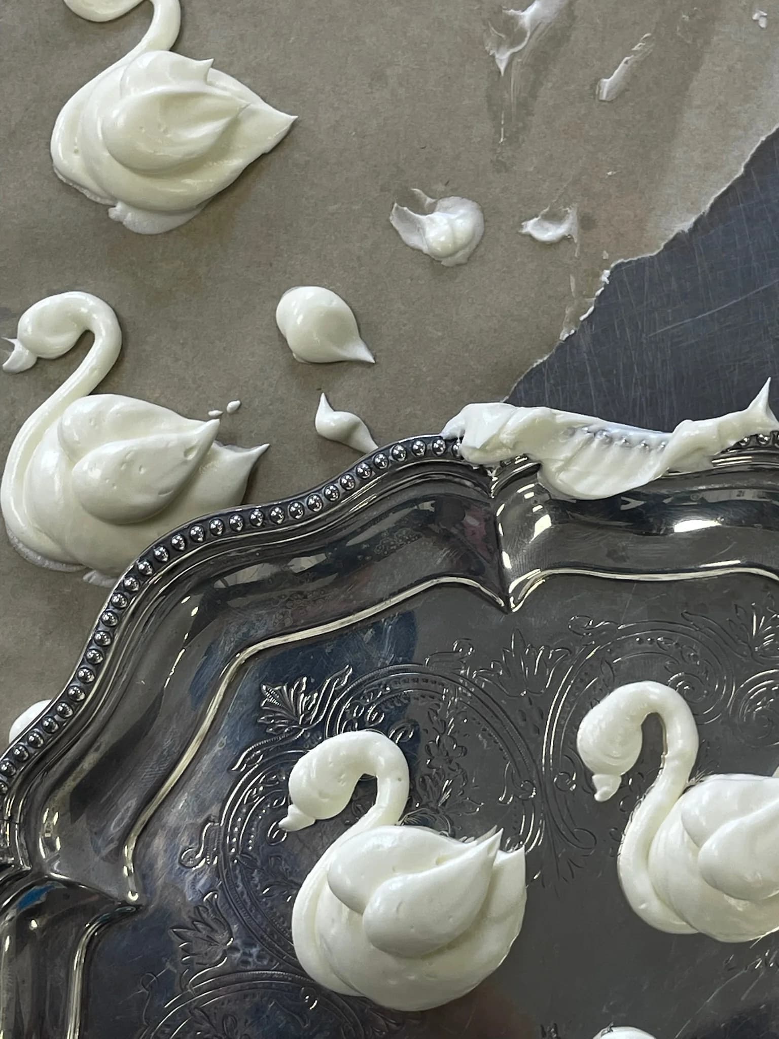 Swan-shaped cake beside silver serving trays
