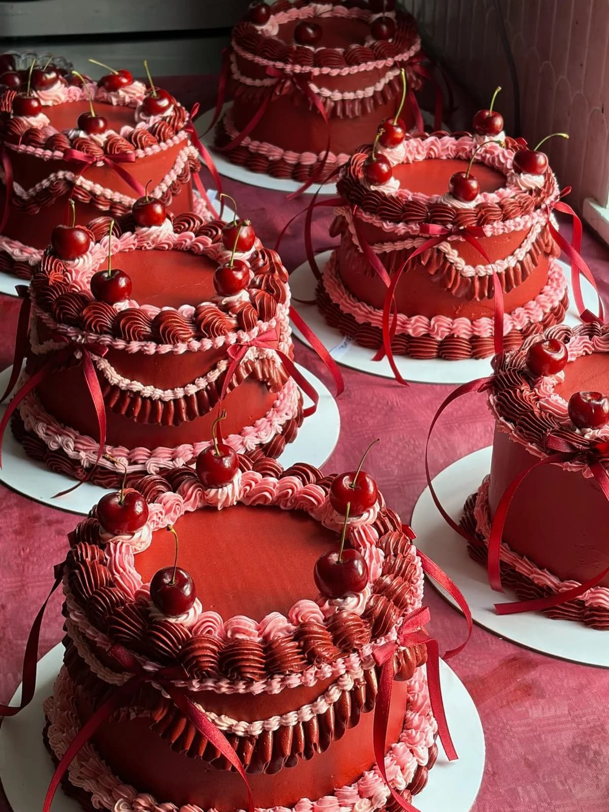 Deep red vintage-style cakes decorated with cherries and pink piping
