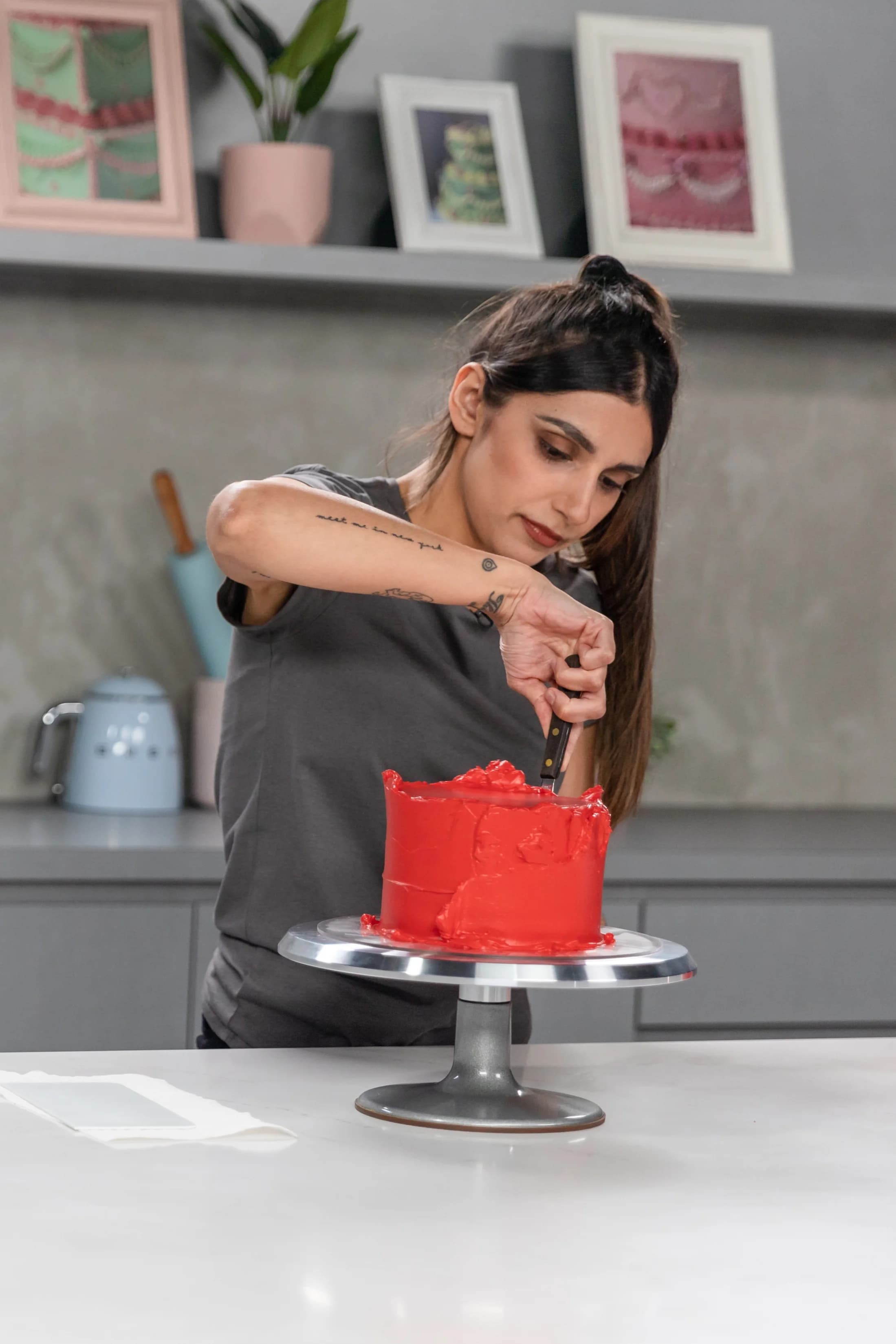 Roxy smoothing bright red buttercream onto a cake