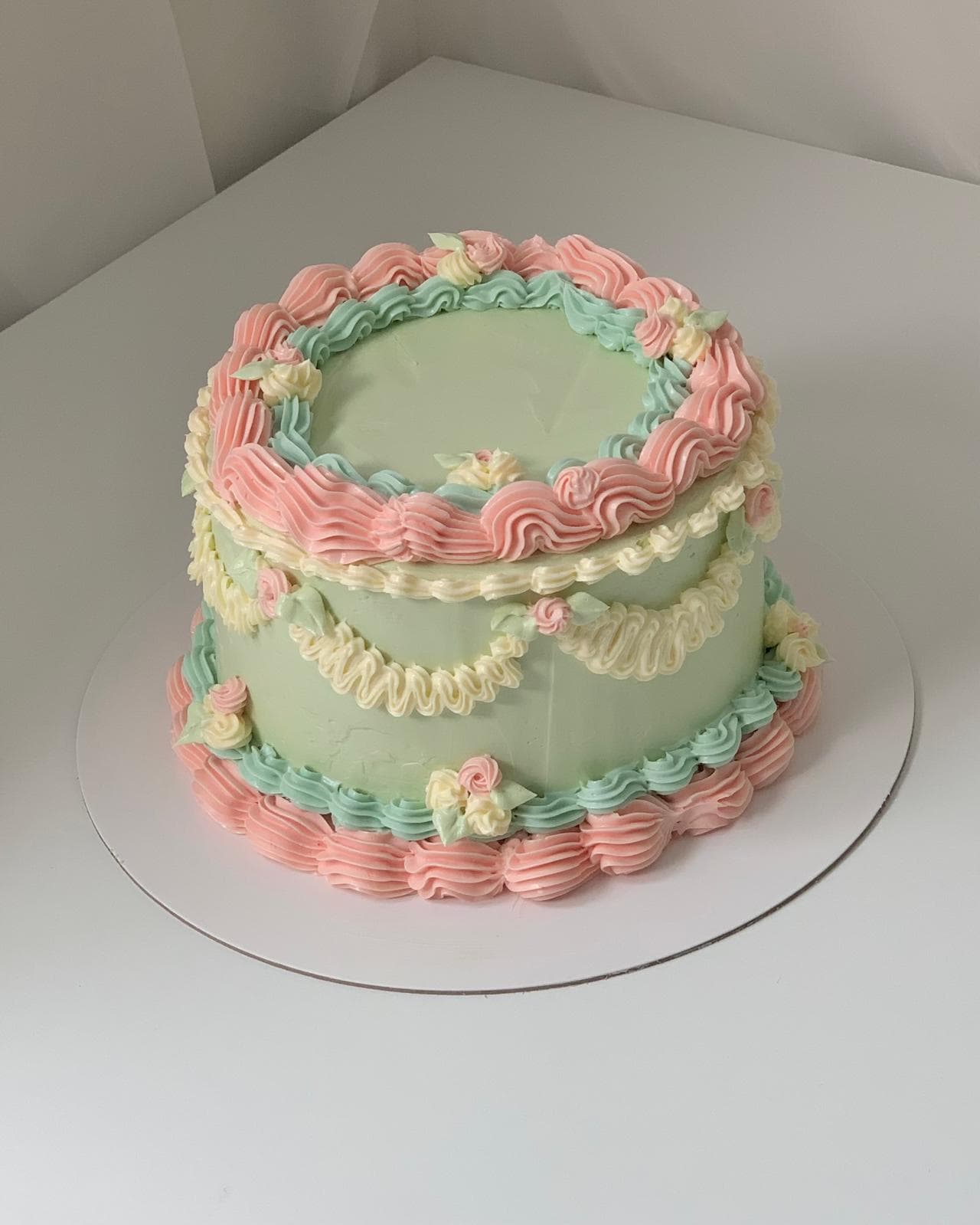 Pastel vintage-style cake with pink and teal buttercream piping made by a student