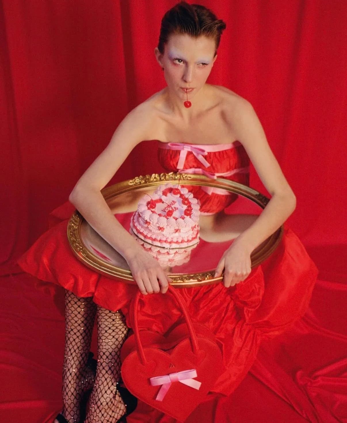 Model in a red dress holding a heart-adorned celebration cake